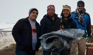 Dallas Parker, left, the Rev. David Wilson and Tim Byington, right, present thermal coats to a camp volunteer at the Oceti Sakawin Camp at Standing Rock. The coats were donated by the Urban Inter-Tribal Center of Texas. 
