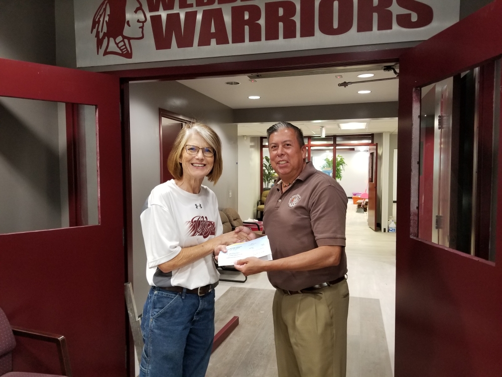 The Rev. David Wilson, OIMC superintendent, provides a check to Dixie Swearingen, superintendent of Webber Falls Public Schools on August 29, 2019.